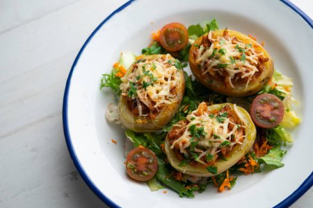 Téléchargez les photos : Pommes de terre farcies à la viande hachée et aux tomates et cuites au four au fromage. - en image libre de droit