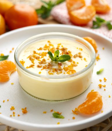 Téléchargez les photos : Mousse de mandarine servie dans un verre décoré de fruits frais et de noix. - en image libre de droit