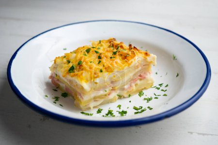 Photo for Potato and bechamel lasagna. Recipe with ham and grilled cheese. - Royalty Free Image