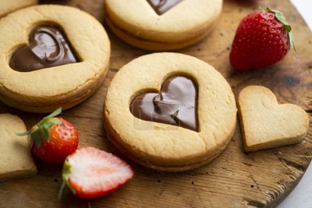 Téléchargez les photos : Biscuits au beurre avec des cœurs remplis de crème au chocolat et de fraises. - en image libre de droit