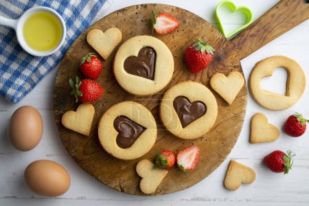 Photo for Butter cookies with hearts filled with chocolate cream and strawberries. - Royalty Free Image