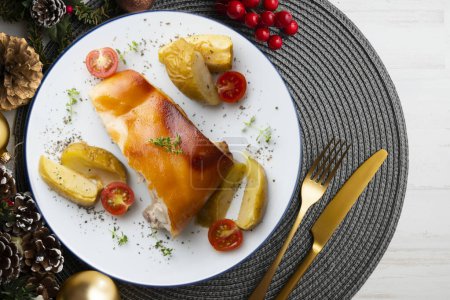 Téléchargez les photos : Ségovie cochon de lait cuit au four avec des pommes. Servi sur une table avec décorations de Noël. - en image libre de droit