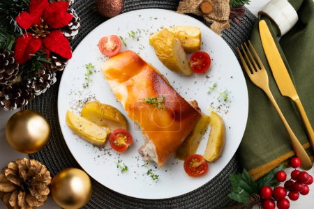 Photo for Segovia suckling pig cooked in the oven with apples. Served on a table with Christmas decorations. - Royalty Free Image