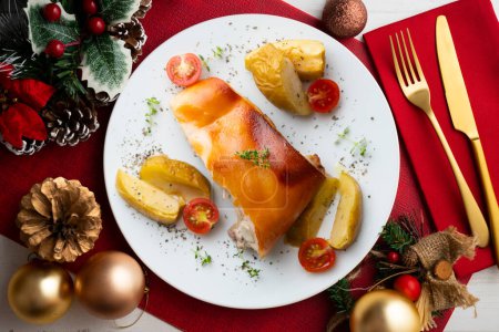 Photo for Segovia suckling pig cooked in the oven with apples. Served on a table with Christmas decorations. - Royalty Free Image