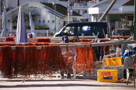 Téléchargez les photos : Nachikatsuura, Japon ; 1er octobre 2023 : Pêcheurs réparant leurs filets de pêche au port de Katsuura à Wakayama. - en image libre de droit