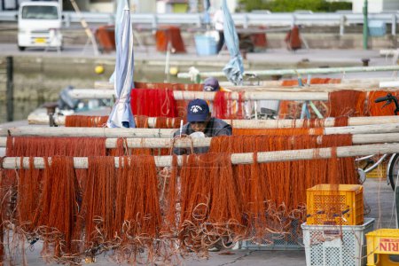 Foto de Nachikatsuura, Japón; 1 de octubre de 2023: Pescadores arreglando sus redes de pesca en el puerto de Katsuura en Wakayama. - Imagen libre de derechos