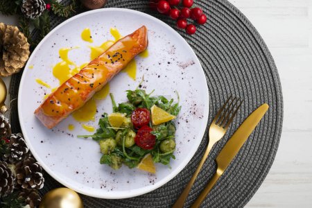 Photo for Grilled salmon with orange sauce and a salad. Typical Mediterranean coast dish. Christmas food served on a table decorated with Christmas motifs. - Royalty Free Image