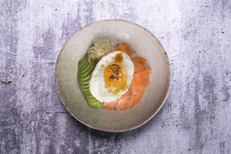 Téléchargez les photos : Donburi au saumon Teriyaki avec oeuf frit, avocat, oignon, poivron rouge et autres légumes. Plat typiquement japonais. - en image libre de droit