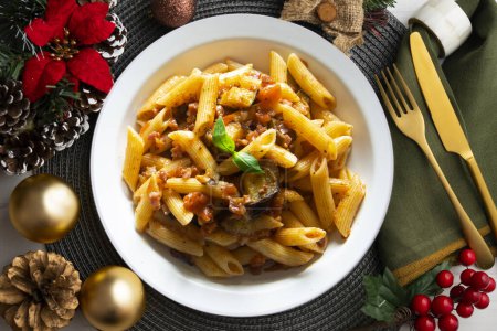 Téléchargez les photos : Pâtes alla norma recette italienne traditionnelle. Plat servi sur une table avec décoration de Noël. - en image libre de droit
