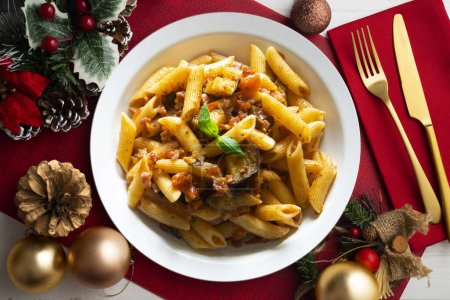 Pasta allá norma receta italiana tradicional. Plato servido sobre una mesa con decoración navideña.