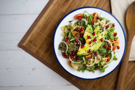 Photo for Argula salad with pasta bows, avocado, cherry tomatoes, pomegranate and sesame. - Royalty Free Image
