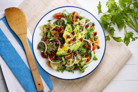 Photo for Argula salad with pasta bows, avocado, cherry tomatoes, pomegranate and sesame. - Royalty Free Image