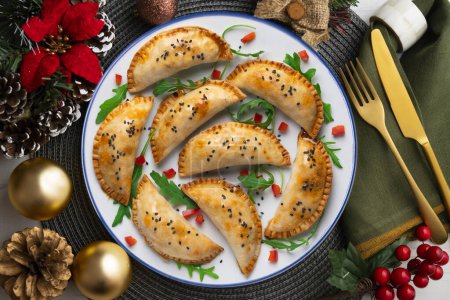 Téléchargez les photos : Empanadas argentines faites à la main avec une recette traditionnelle. Nourriture de Noël sur une table décorée d'ornements. - en image libre de droit