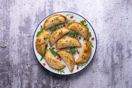 Téléchargez les photos : Empanadas argentines faites à la main avec une recette traditionnelle. Plan aérien décoré de poivron rouge et de roquette. - en image libre de droit