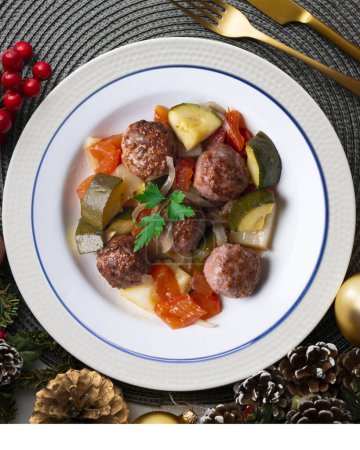 Téléchargez les photos : Boulettes de viande avec sauce tomate et légumes. Nourriture de Noël sur une table avec décorations. - en image libre de droit