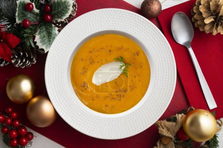 Photo for Carrot and pumpkin cream with cream and nuts. Christmas food served on a table decorated with Christmas motifs. - Royalty Free Image