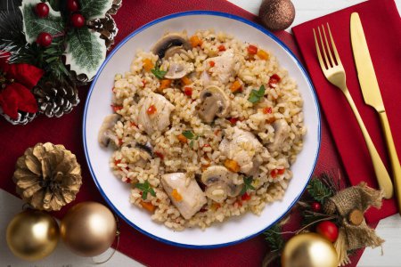 Téléchargez les photos : Paella de riz avec dinde et légumes. Une recette saine. Nourriture de Noël servie sur une table décorée de motifs de Noël. - en image libre de droit