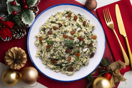 Foto de Arroz con espinacas y pasas. receta vegana. Comida navideña servida sobre una mesa decorada con motivos navideños. - Imagen libre de derechos