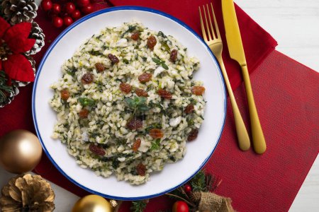 Téléchargez les photos : Riz aux épinards et raisins secs. recette végétalienne. Nourriture de Noël servie sur une table décorée de motifs de Noël. - en image libre de droit