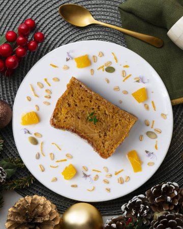 Photo for Delicious vegan carrot and tangerine sponge cake with ground almonds. Christmas food served on a table decorated with Christmas motifs. - Royalty Free Image