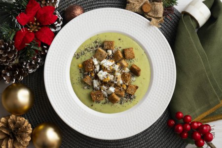 Photo for Artichoke cream with bread croutons. Typical Spanish vegan tapas.. Christmas food served on a table decorated with Christmas motifs. - Royalty Free Image