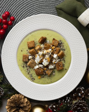 Photo for Artichoke cream with bread croutons. Typical Spanish vegan tapas.. Christmas food served on a table decorated with Christmas motifs. - Royalty Free Image