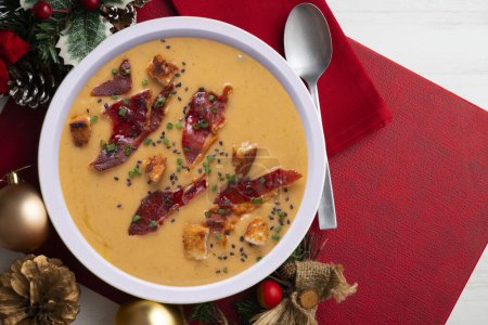 Photo for Traditional spanish salmorejo. Cold tomato soup served with egg and iberico jam. Christmas food served on a table decorated with Christmas motifs. - Royalty Free Image