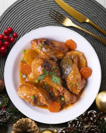 Photo for Chicken thighs cooked in the oven with vegetables. Food served on a table with Christmas decorations. - Royalty Free Image