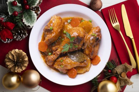 Téléchargez les photos : Cuisses de poulet cuites au four avec des légumes. Nourriture servie sur une table avec des décorations de Noël. - en image libre de droit