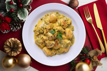 Foto de Pollo cocido con leche de coco y curry. Comida servida en una mesa con decoraciones navideñas. - Imagen libre de derechos
