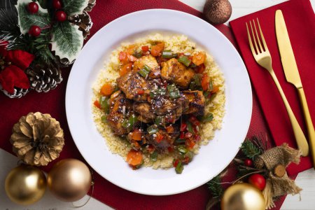 Foto de Pollo marinado al estilo marroquí con cuscús. Comida servida en una mesa con decoraciones navideñas. - Imagen libre de derechos