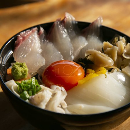 Téléchargez les photos : Japonaise sashimi donburi au poisson blanc, calmar et jaune d'oeuf sur un lit de riz blanc. - en image libre de droit