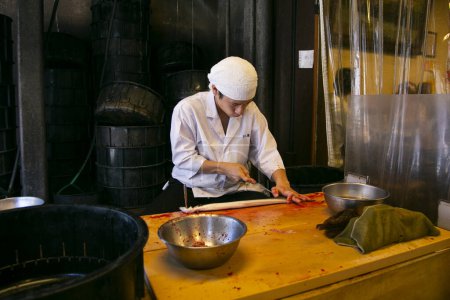 Téléchargez les photos : Narita, Japon ; 1er octobre 2023 : Chef japonais préparant et nettoyant une anguille. L'anguille fumée grillée est la nourriture la plus traditionnelle à Narita. - en image libre de droit
