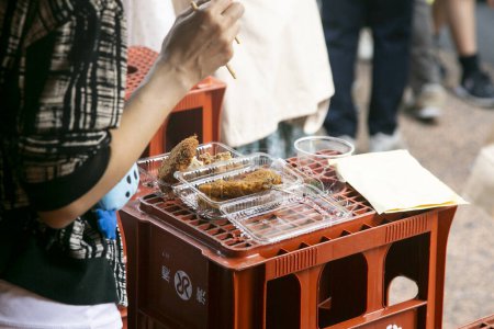 Photo for A person enjoying some street food in Yanaka street food market in Tokyo. - Royalty Free Image