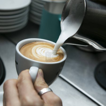 Téléchargez les photos : Barista professionnel travaillant avec une machine à café et préparant des boissons chaudes avec du café et du lait. - en image libre de droit