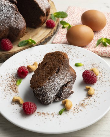 Photo for Delicious and fluffy round chocolate cake with cashews and raspberries. - Royalty Free Image
