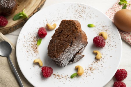 Foto de Delicioso y esponjoso pastel de chocolate redondo con anacardos y frambuesas. - Imagen libre de derechos