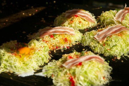Foto de Okonomiyaki es un salado panqueque de col japonesa a la parrilla como te gusta con su elección de proteínas y sabrosos condimentos y coberturas. - Imagen libre de derechos