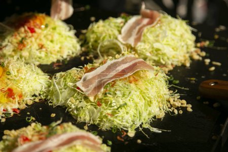 Photo for Okonomiyaki is a savory Japanese cabbage pancake grilled as you like it with your choice of protein and tasty condiments and toppings. - Royalty Free Image