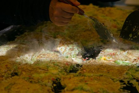 Foto de Okonomiyaki es un salado panqueque de col japonesa a la parrilla como te gusta con su elección de proteínas y sabrosos condimentos y coberturas. - Imagen libre de derechos