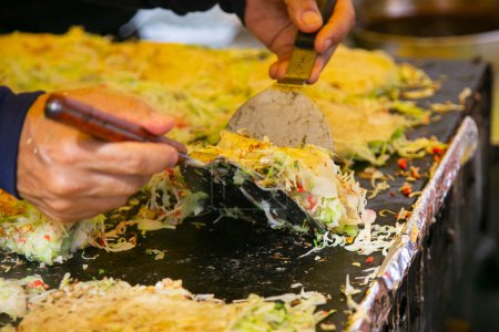 Téléchargez les photos : Okonomiyaki est une crêpe au chou japonais salé grillé comme vous l'aimez avec votre choix de protéines et de condiments savoureux et garnitures. - en image libre de droit