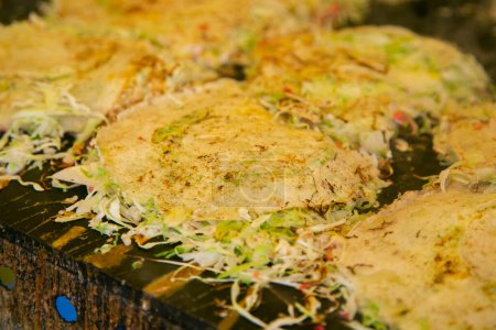 Okonomiyaki is a savory Japanese cabbage pancake grilled as you like it with your choice of protein and tasty condiments and toppings.