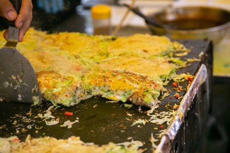 Photo for Okonomiyaki is a savory Japanese cabbage pancake grilled as you like it with your choice of protein and tasty condiments and toppings. - Royalty Free Image