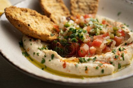 Photo for Traditional chickpea hummus with cut pepper and onion in the center served with toast. - Royalty Free Image