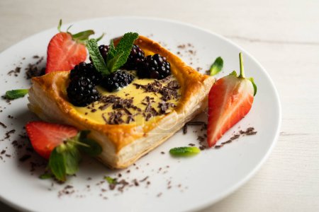 Téléchargez les photos : Dessert pâtissier feuilleté aux fraises et aux mûres rempli de crème pâtissière. - en image libre de droit