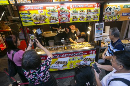 Photo for Osaka, Japan; 20th October 2023: Takoyaki Restaurant in Dontonbori district with tourists. - Royalty Free Image