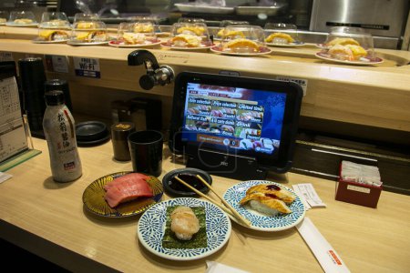Foto de Osaka, Japón; 20 de octubre de 2023: Kaitenzushi es un restaurante de sushi donde los platos se colocan en una cinta transportadora que recorre el restaurante.. - Imagen libre de derechos