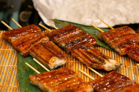 Photo for Roasted skewered eel at a food market in the city of Osaka in Japan. - Royalty Free Image