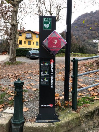 Foto de Argegno-Lombardia-Italia - 13 de diciembre de 2022 - Desfibrilador Externo Automatizado (DEA) en el puesto de asistencia en la calle con botón de llamada al hospital para emergencias - Imagen libre de derechos