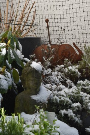 Foto de Buda cubierto de nieve y elefante cubierto de nieve en un balcón lleno de plantas - Imagen libre de derechos